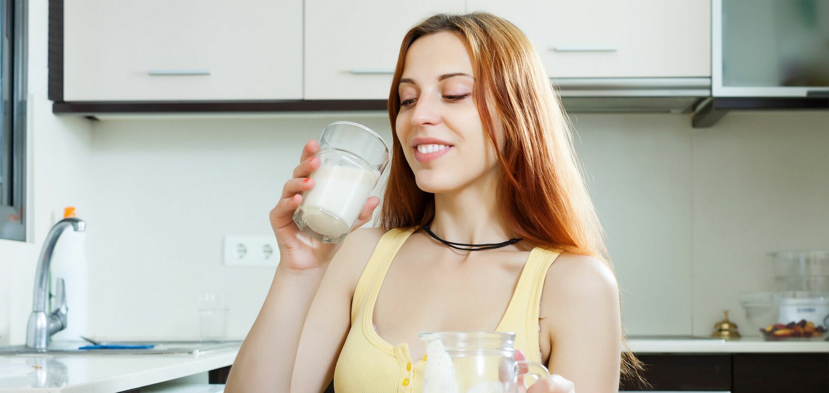 A woman drinking a shake in a kitchen